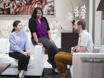 3 professionals talking smiling with artwork in background