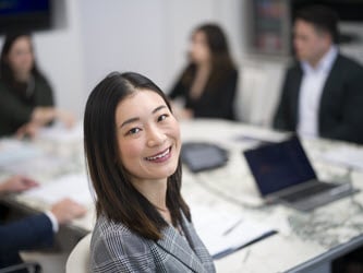 1 attorney looking back over shoulder while others meet around conference room table