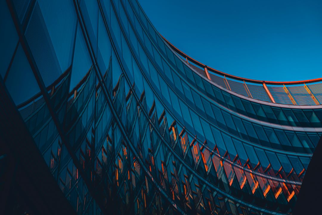 Glass building facade with blue and orange highlights in front of a dark blue sky background