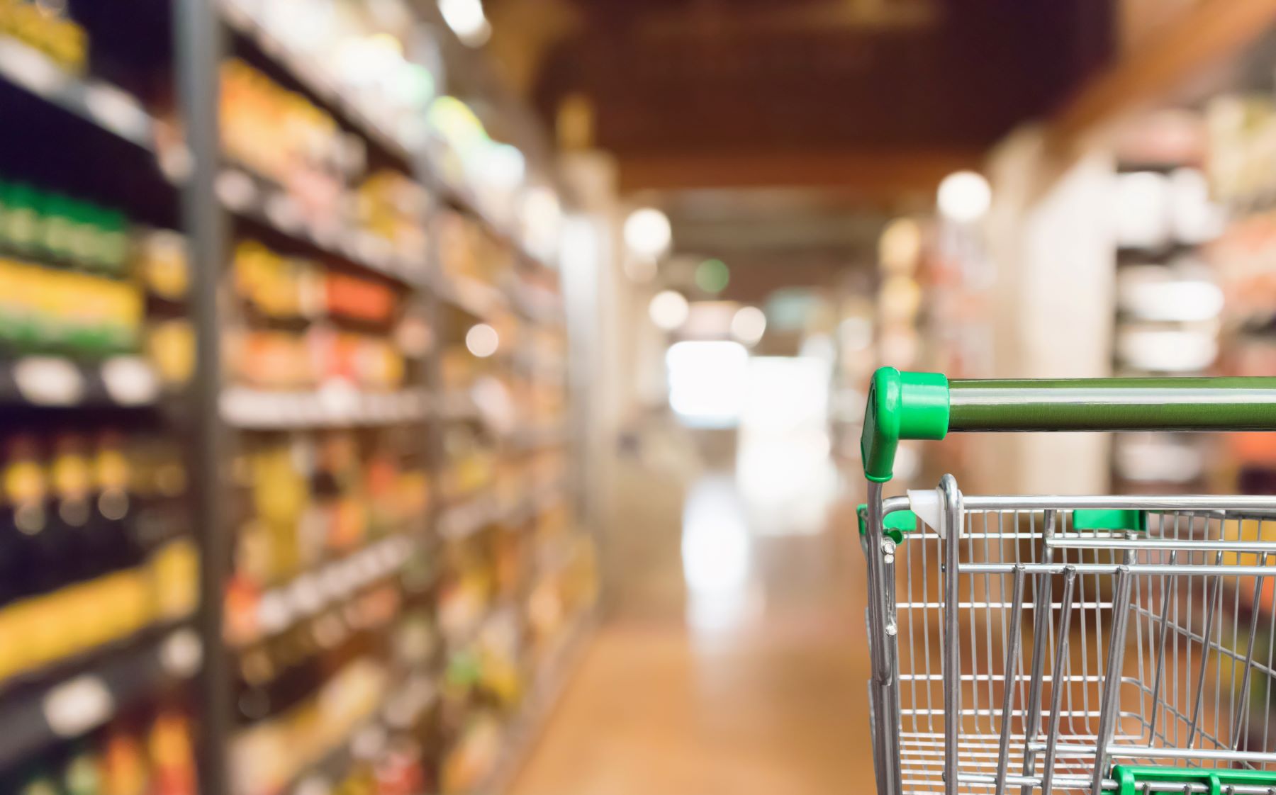 Shopping cart in foreground of grocery aisle